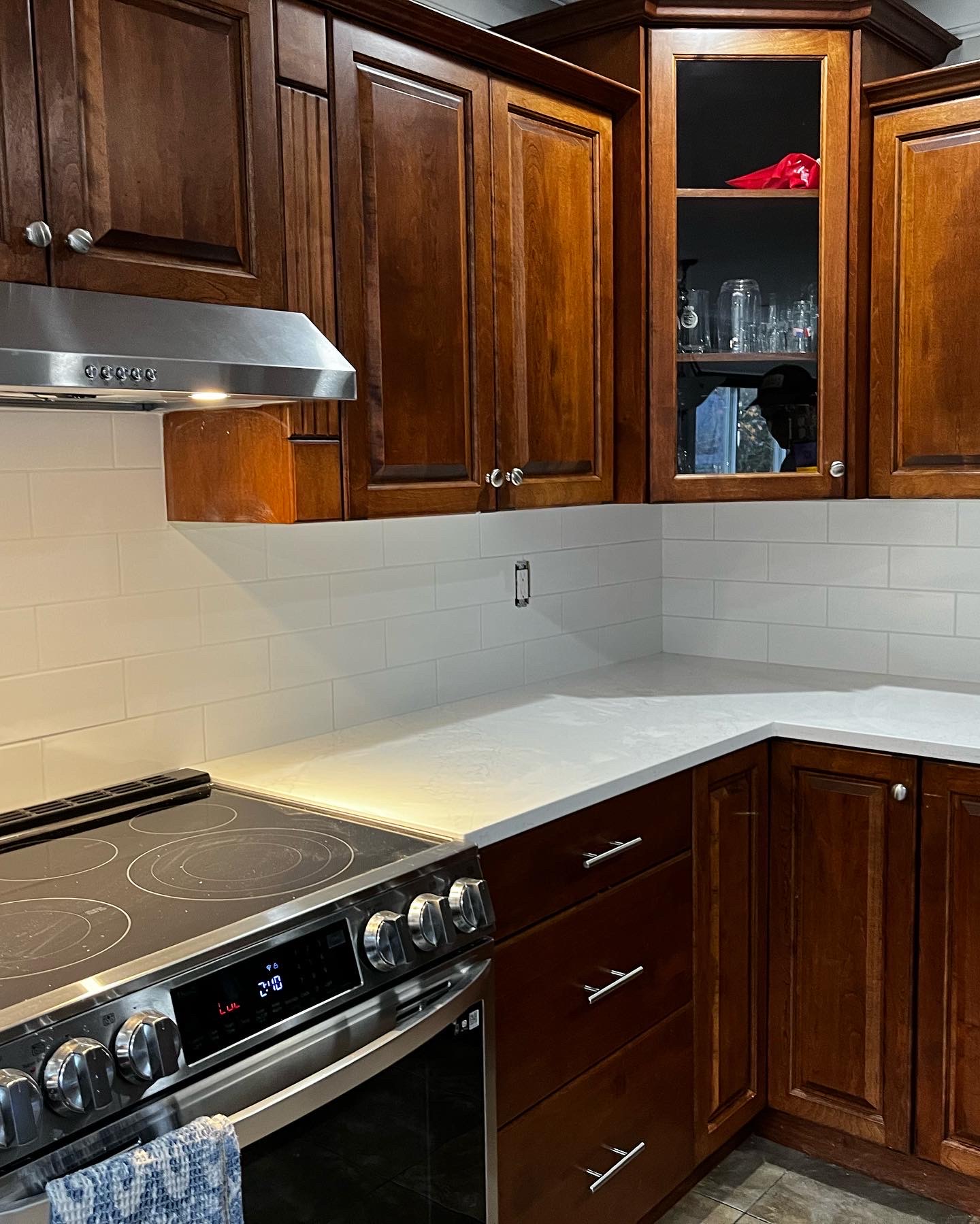 White Quartz counters and white subway tile backsplash complete a contrast with dark wood cabinets