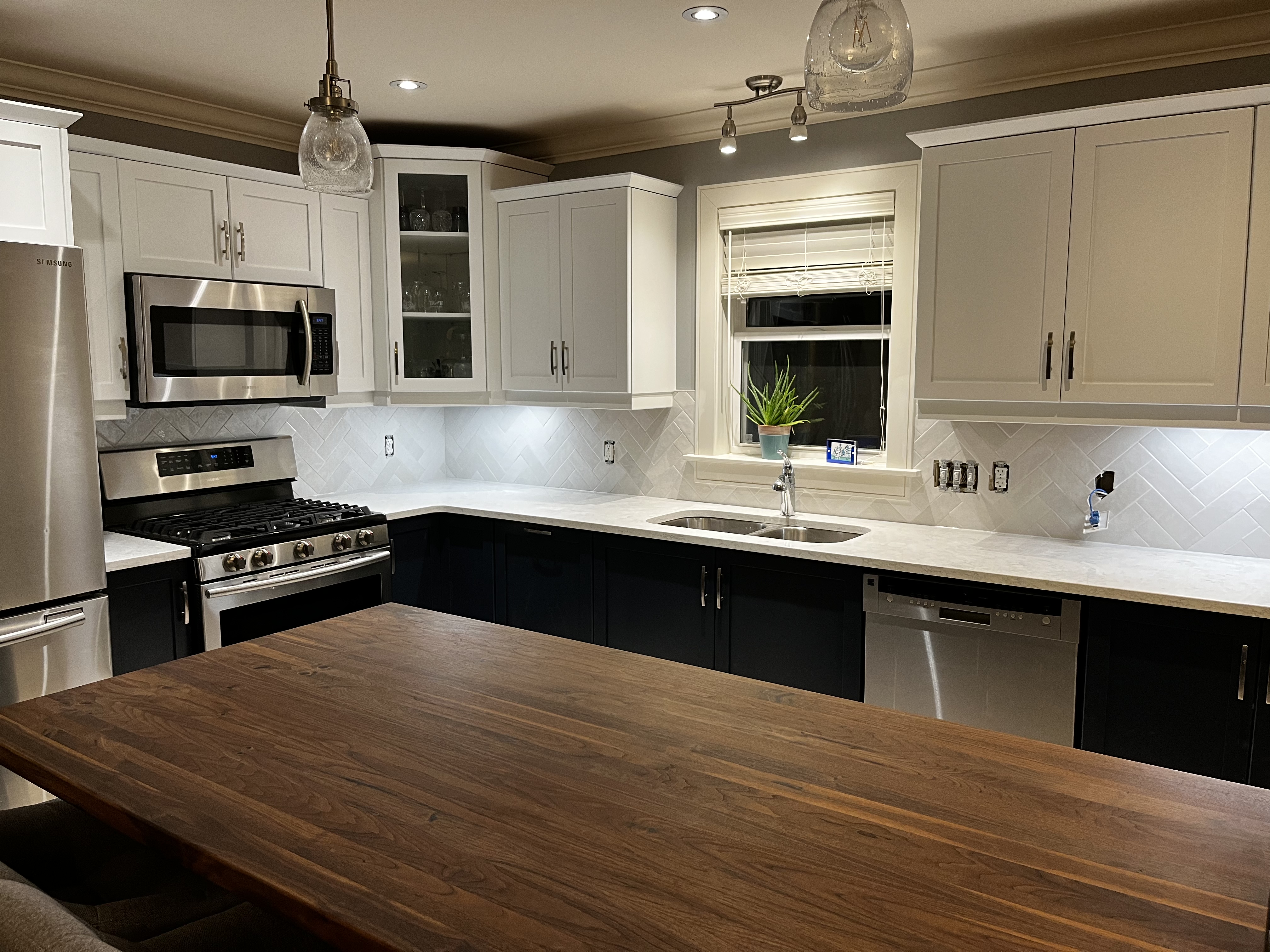 Who says you can’t have it all?  Quartz countertop, Butcher Block island, black lower cabinets, white upper cabinets, and a herringbone tile backsplash
