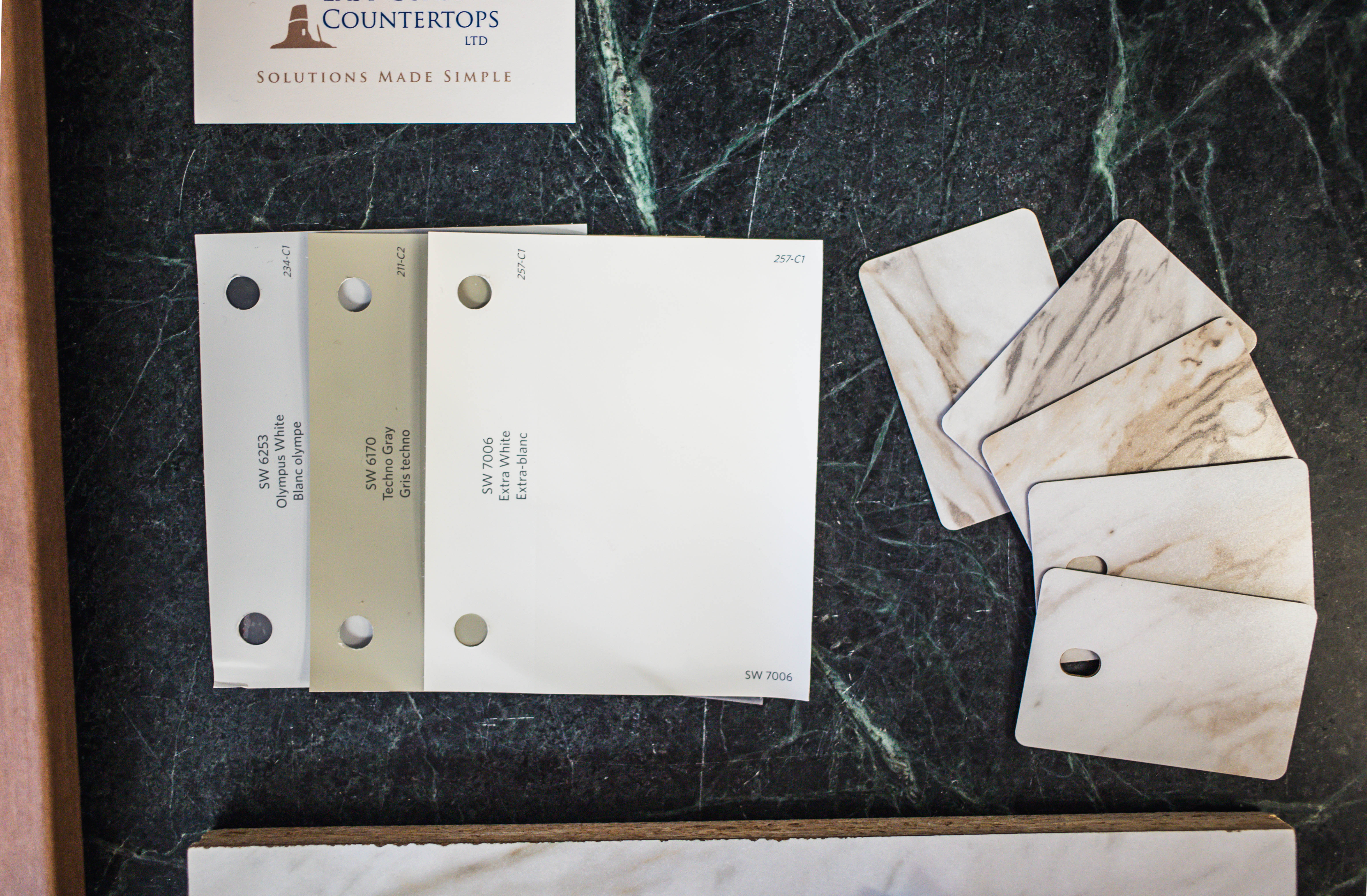 A flat lay photography image of the Drama Marble countertop, along with paint swatches, cabinet door, and tile swatches that are mentioned in the blog article.