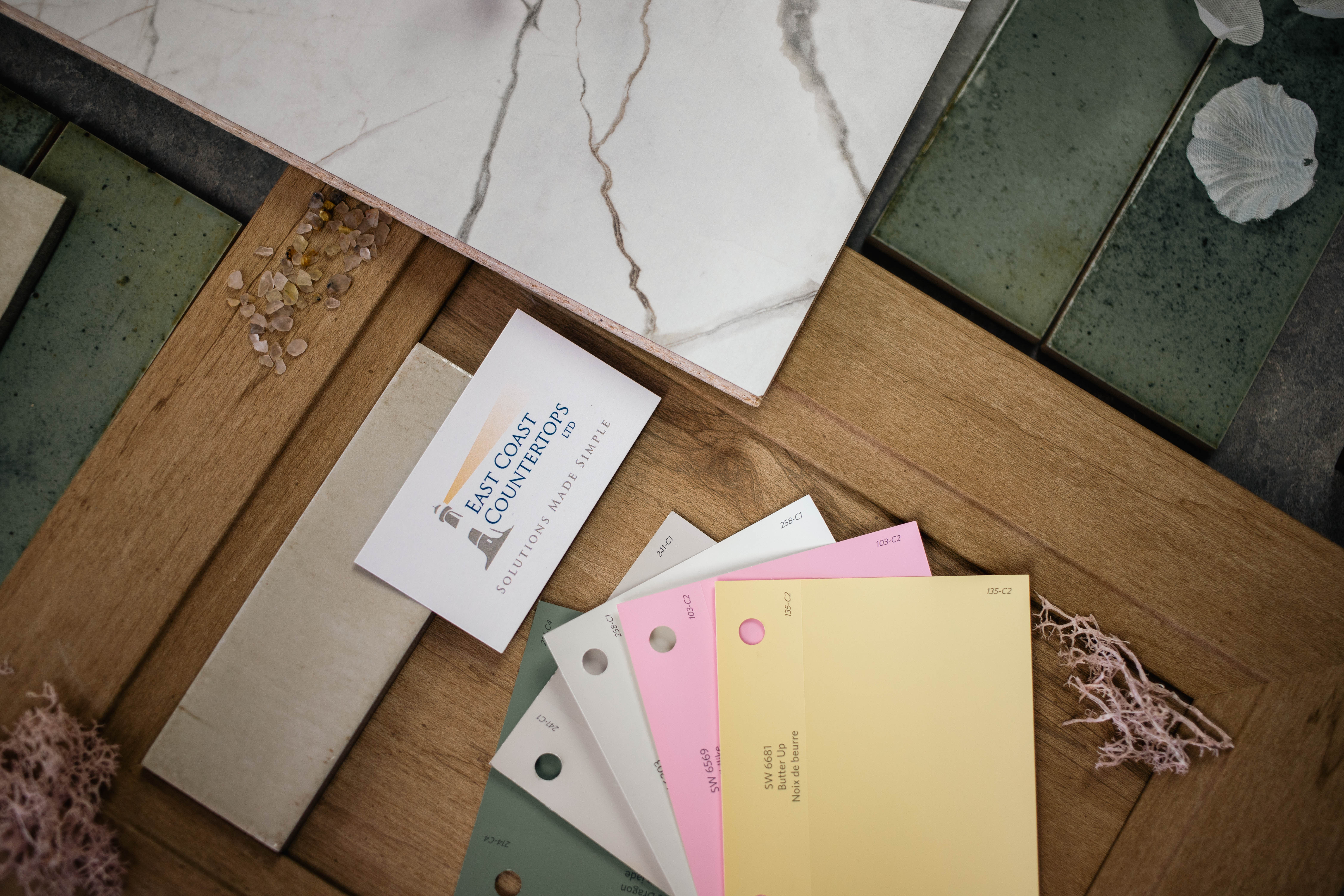 Flat lay photography of fractured marble countertop with spring colours such as green white pink and yellow with oak cabinet doors and green and cream coloured tiles. 